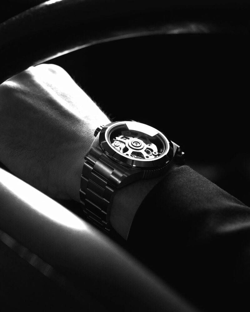 A skeleton sports watch worn at the wheel of a car